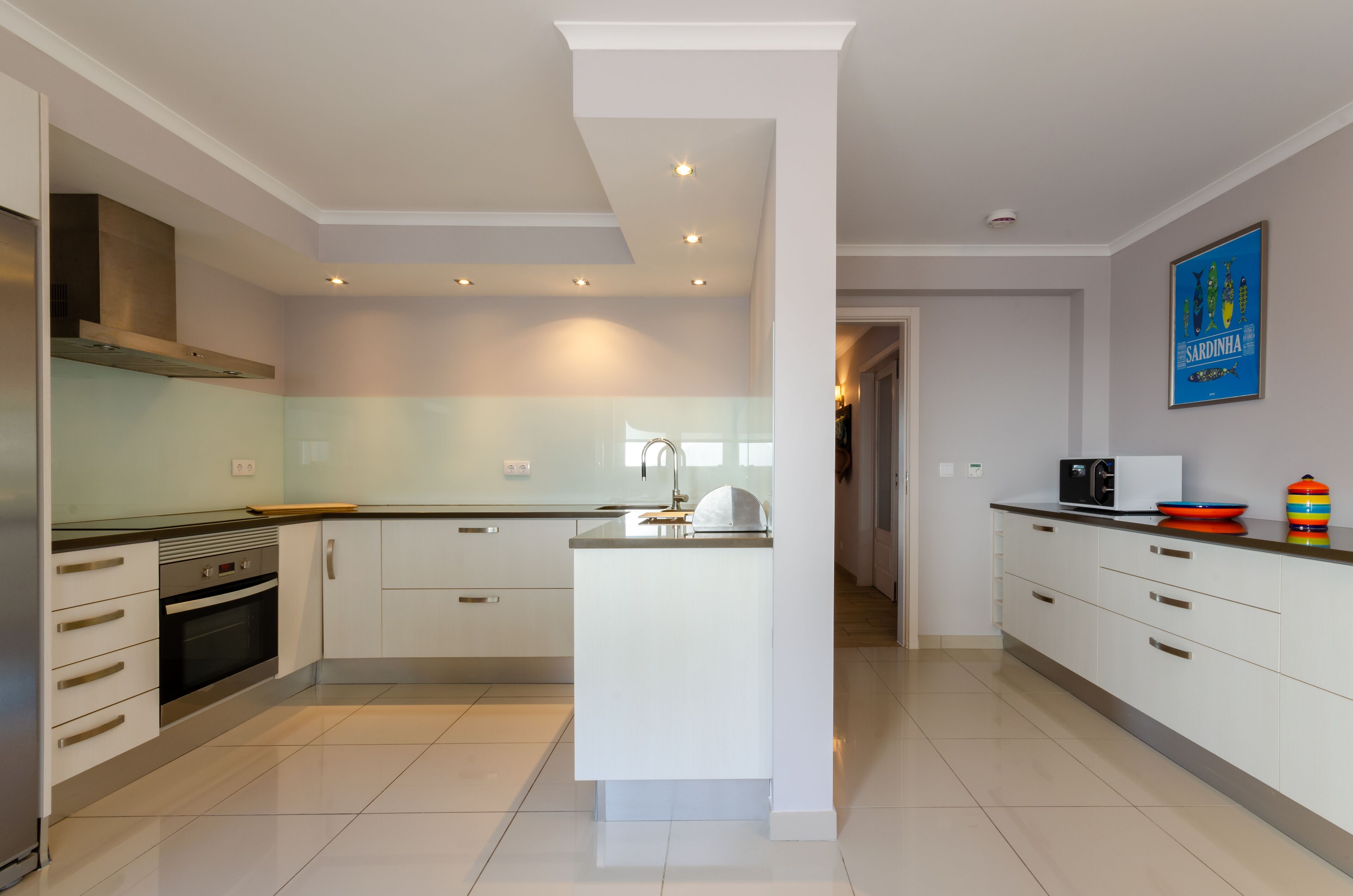 A modern kitchen with white cabinetry, a central island, stainless steel appliances, and a bright, well-lit space.