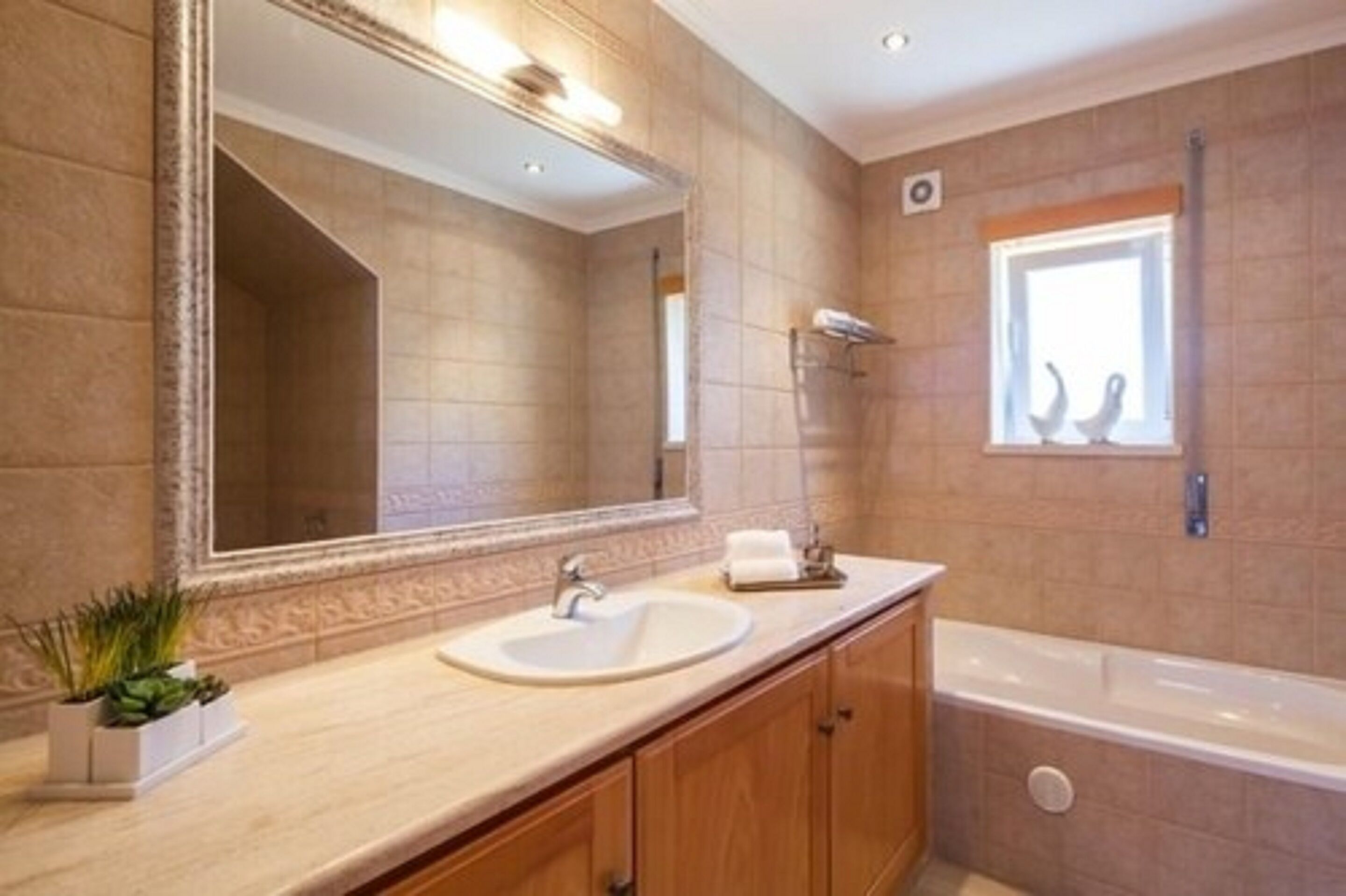 Ein modernes Badezimmer mit großem Spiegel, Waschbecken und Badewanne.