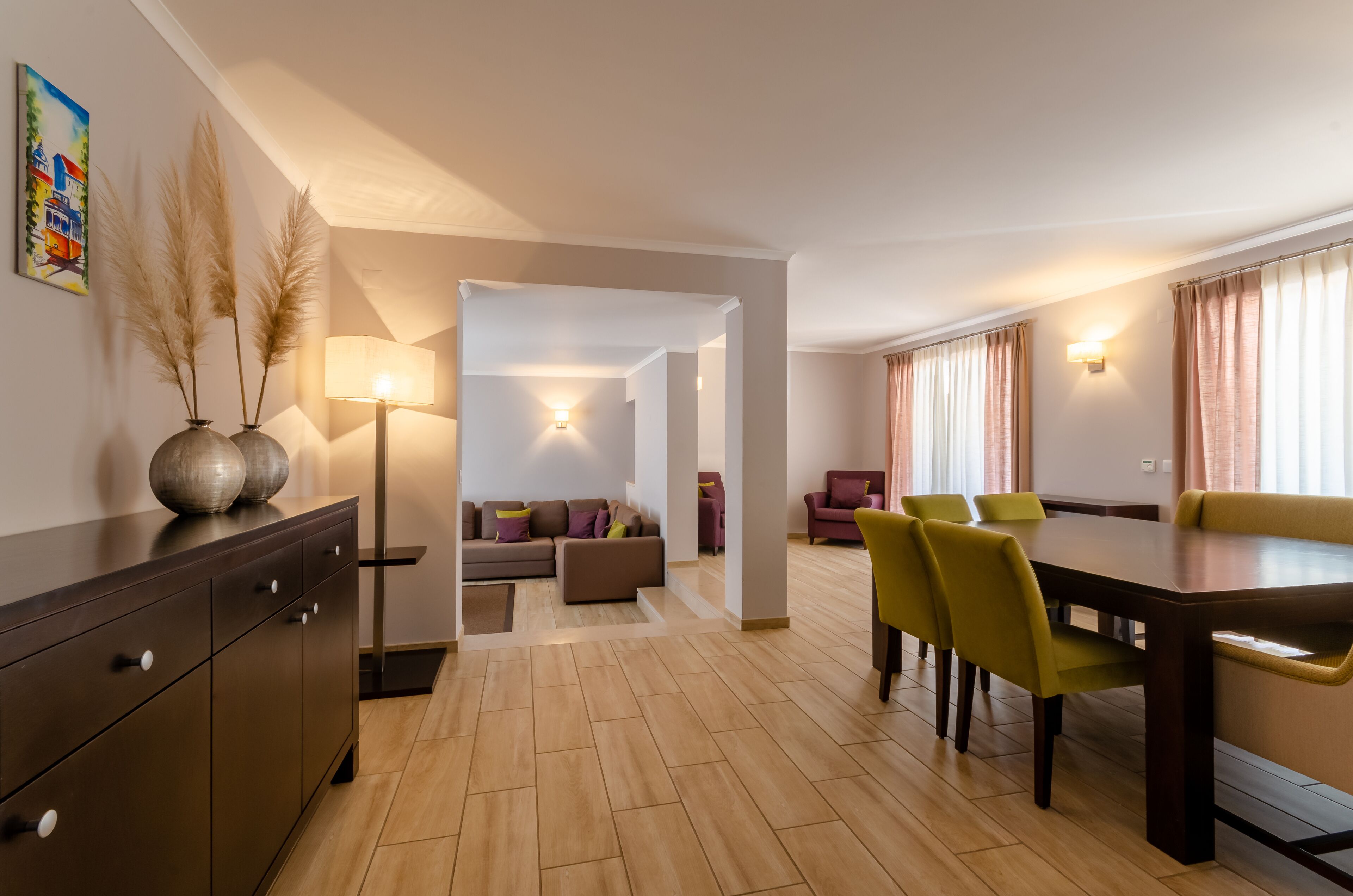 A modern living room with a sofa, a dining table with chairs, and a lamp.