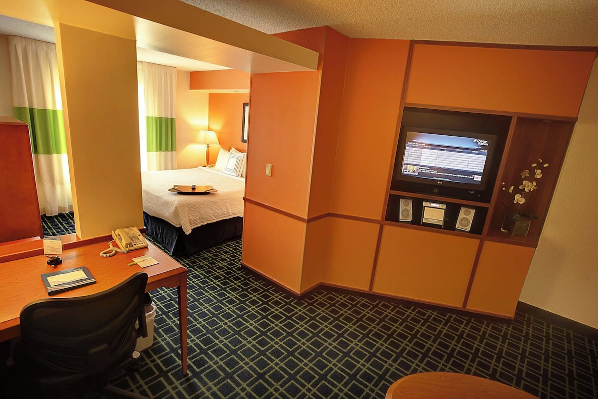 Ein Hotelzimmer mit Bett, Schreibtisch mit Telefon, Fernseher und einer kleinen Sitzecke.