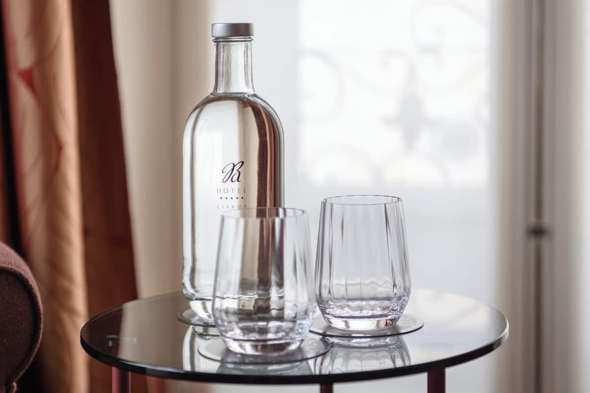 Una botella de licor del Hotel Lisboa y dos vasos sobre una mesa redonda.