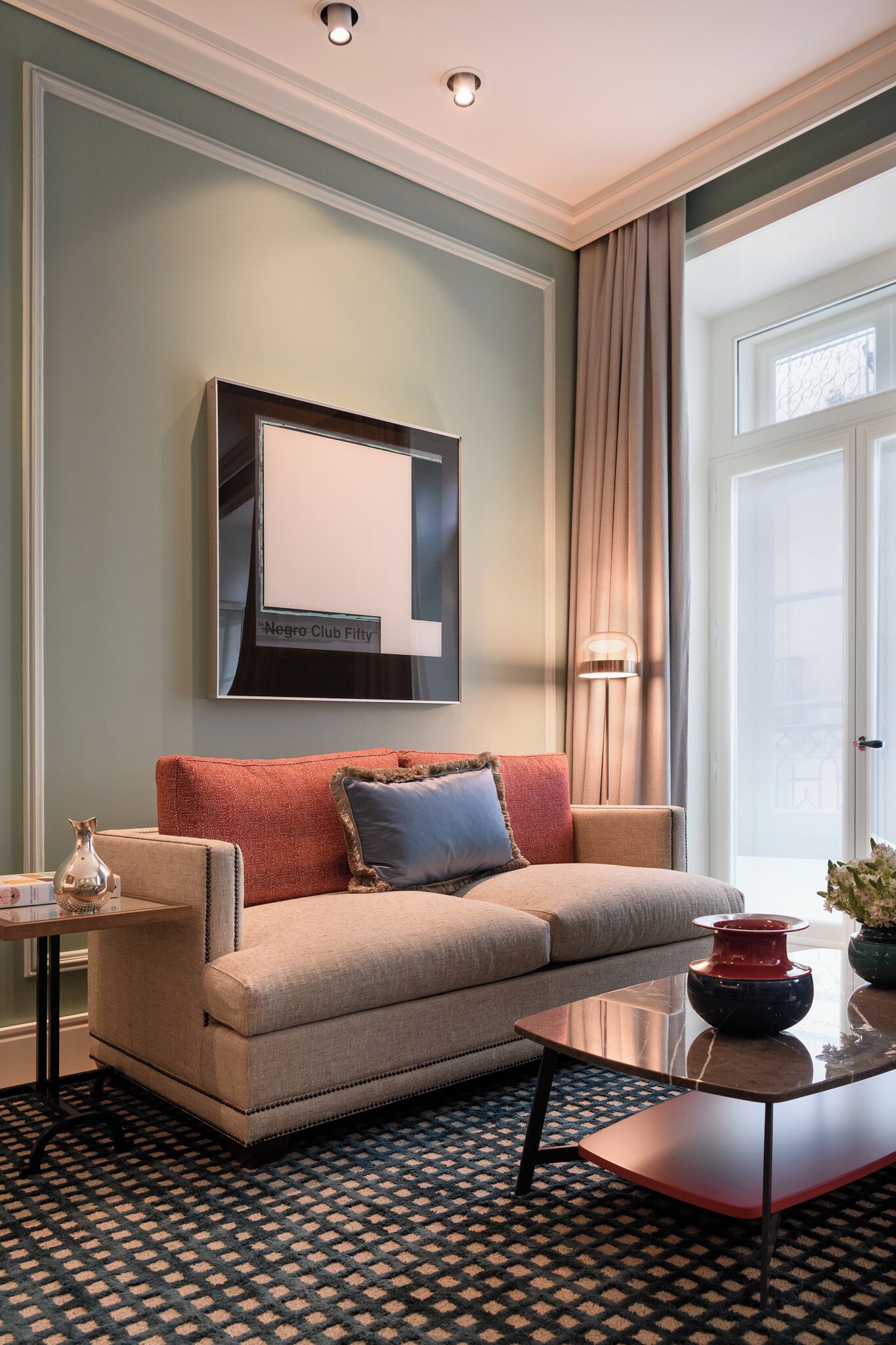 Un salon comprenant un canapé, une table basse, un lampadaire et une œuvre d’art encadrée accrochée au mur.