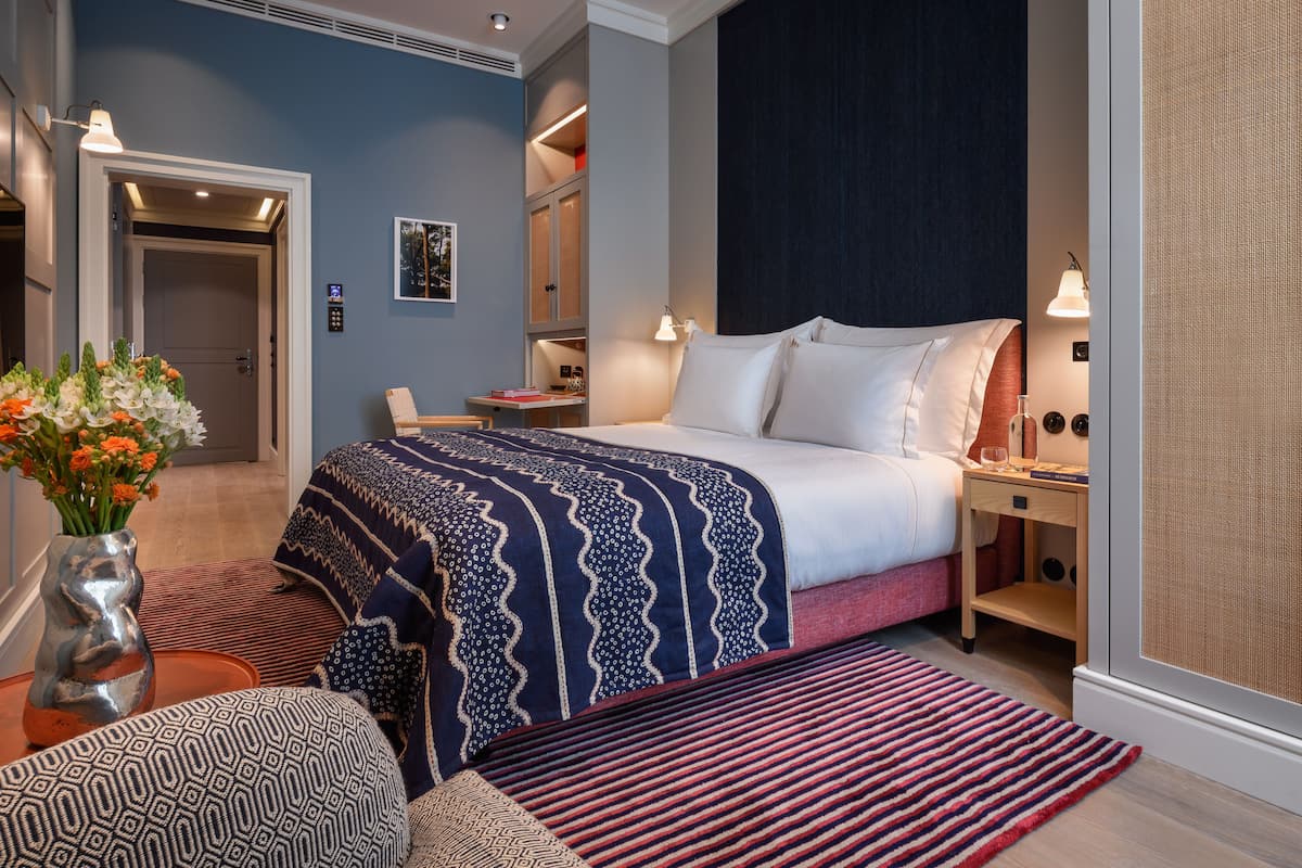 Una habitación de hotel moderna con una cama grande, una mesita de noche, una silla y un escritorio.