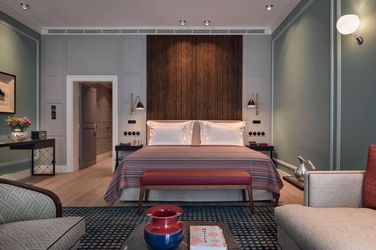 Una habitación de hotel moderna con una cama grande, mesitas de noche, un escritorio y una silla.