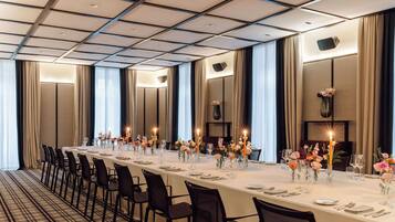 A long banquet table set for a formal event, with chairs aligned on both sides.