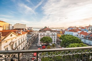 Une vue urbaine mettant en valeur un bâtiment imposant, doté d’un toit rouge et d’un balcon, et entouré d’autres bâtiments présentant des styles architecturaux similaires.
