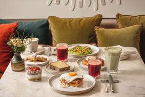 Une table à manger avec différents plats, des boissons et un vase rempli de fleurs.