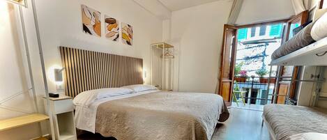 A hotel room with a large bed, a bedside table, a wall-mounted light, and a window with a view of the outside.