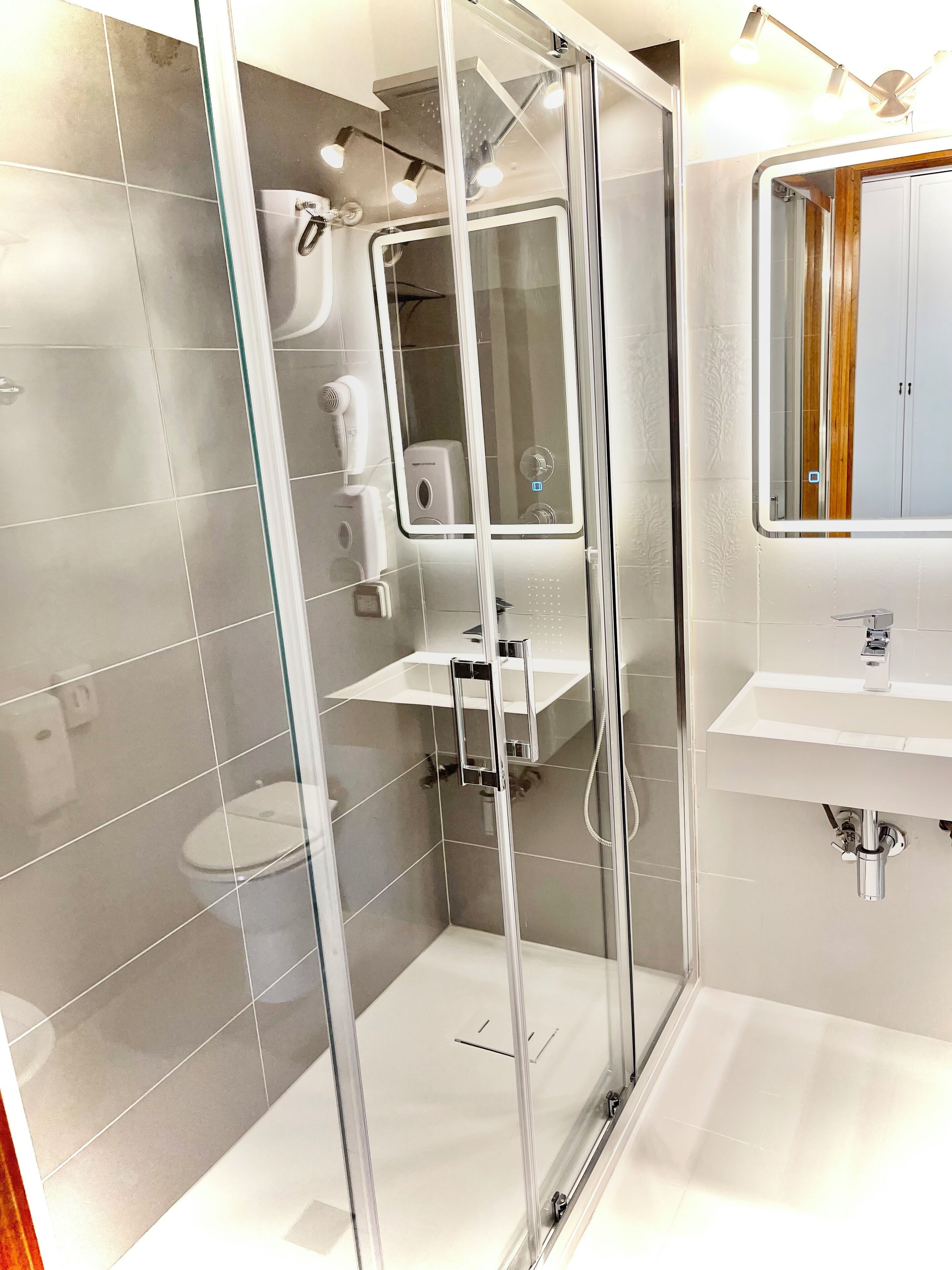 A modern bathroom with a glass-enclosed shower, a white sink, and a mirror above the sink.
