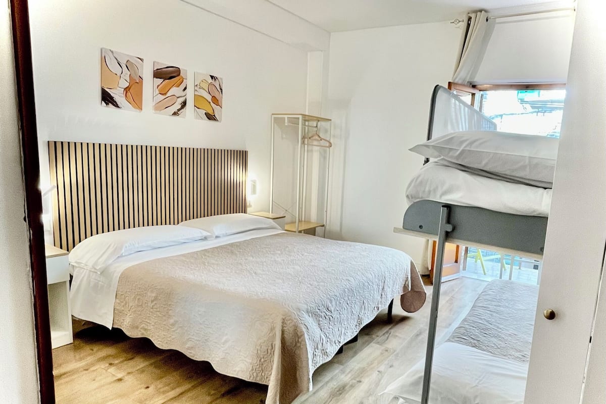 Une chambre à coucher comprenant un lit, une table de chevet, une armoire et un portant à vêtements.