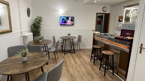 A modern kitchen with a bar area, wooden flooring, and a television mounted on the wall. - Hotel Sant'Ercolano (Perugia)