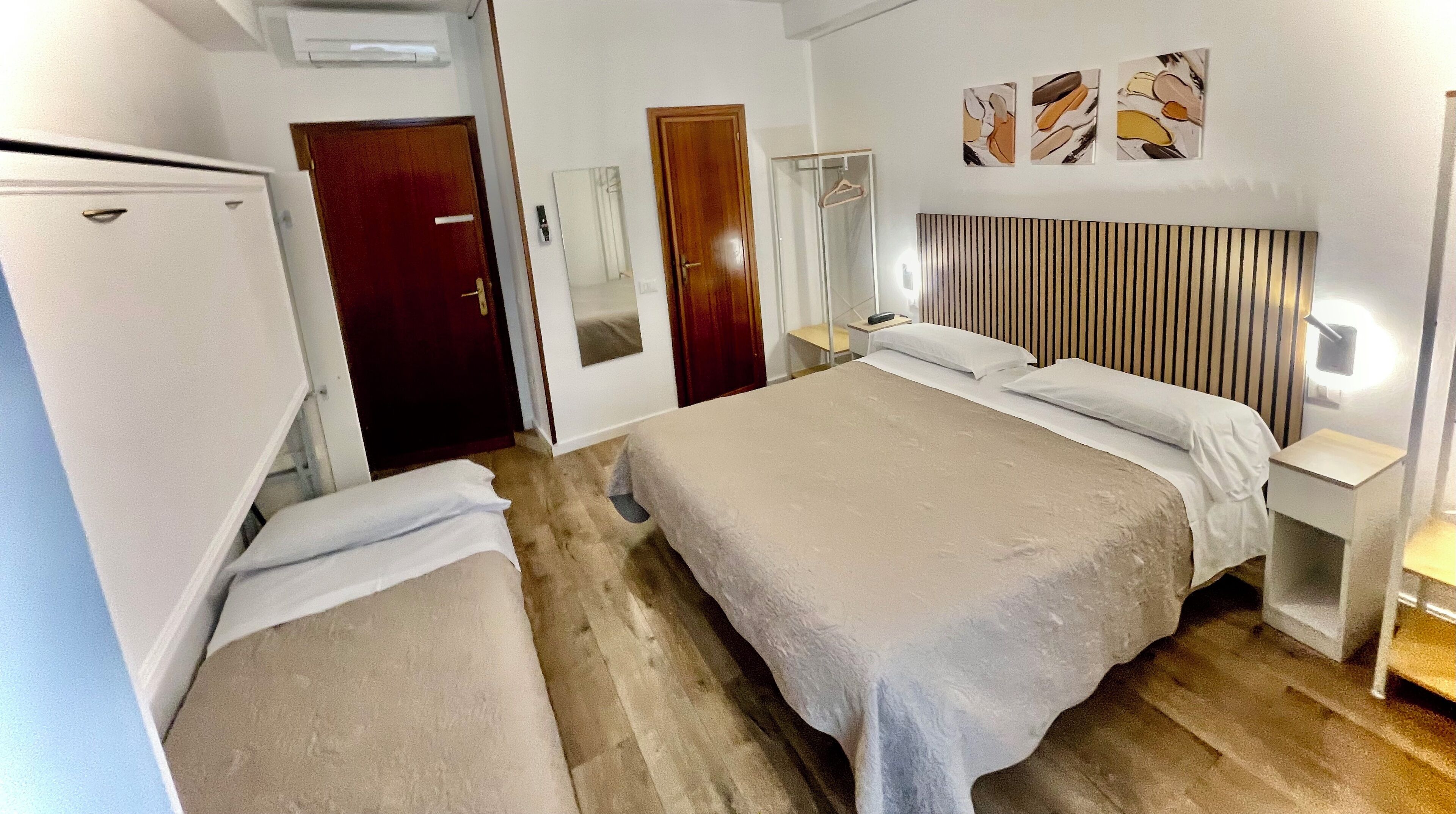 A hotel room with a bed, bedside tables, a wardrobe, and a shower area.