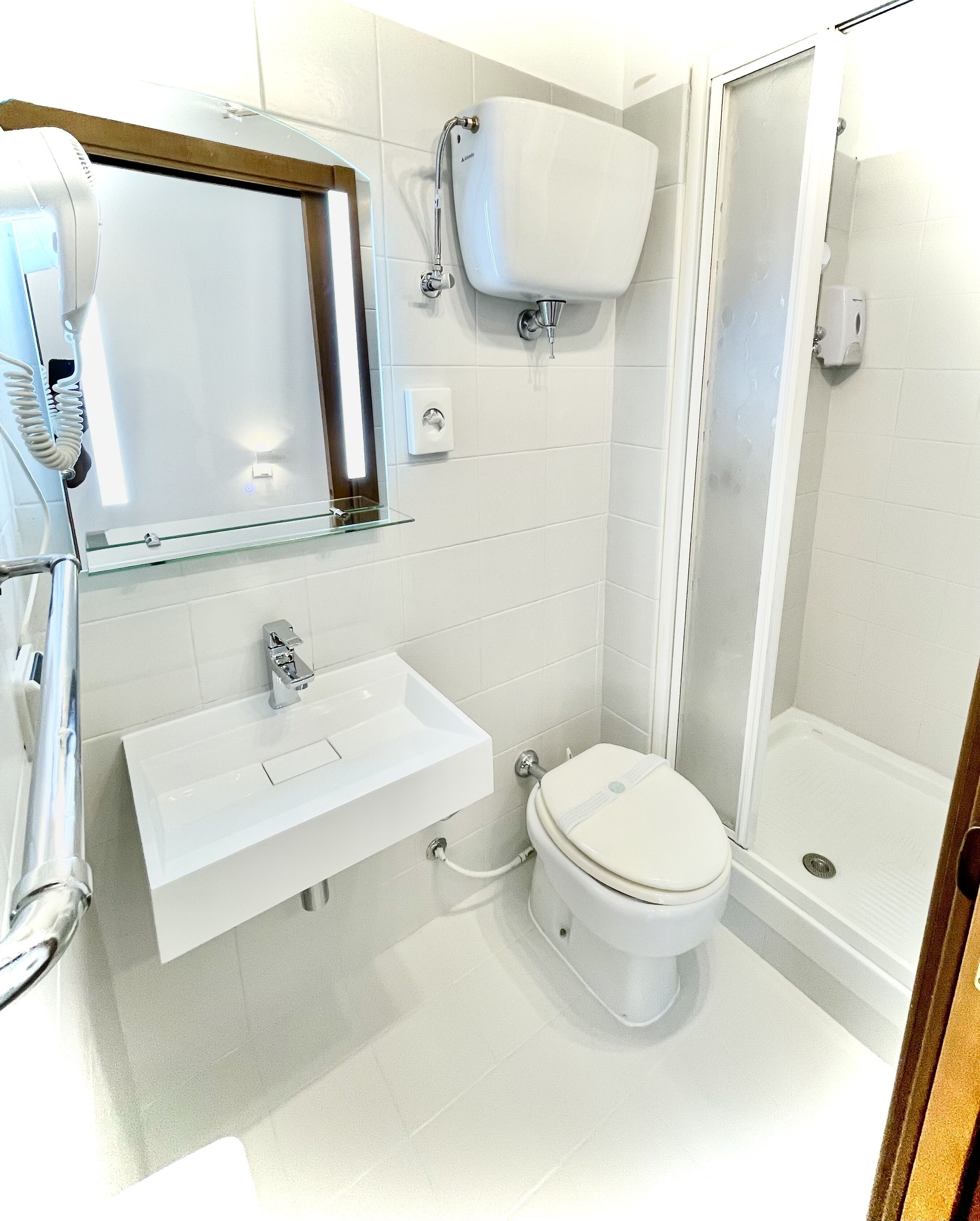 Un baño moderno con cabina de ducha de vidrio, un lavabo blanco y un inodoro.