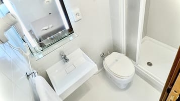 A modern bathroom with a glass-enclosed shower, a toilet, a sink, and a towel rack.