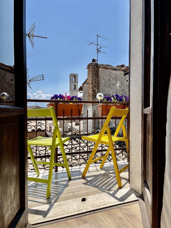 A balcony with yellow chairs, a view of a church tower, and a building with antennas. - Hotel Sant'Ercolano (Perugia)