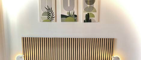 A hotel room with two beds, a striped headboard, bedside lamps, and abstract wall art.