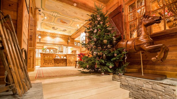 A staircase leading to a wooden interior with a Christmas tree and a horse sculpture. - Hotel Alpen Ruitor (Les Allues)