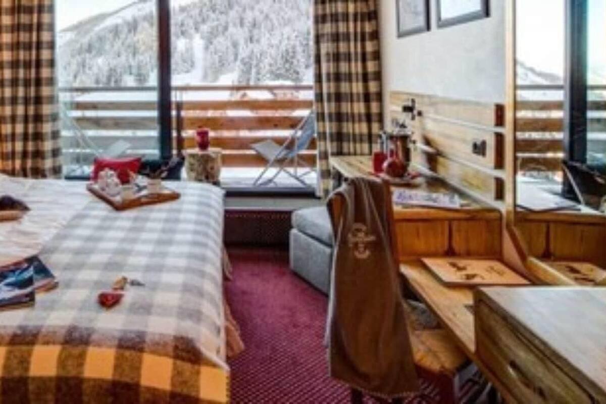 Une chambre d’hôtel avec un lit, un bureau, une chaise et une fenêtre donnant sur des arbres couverts de neige.