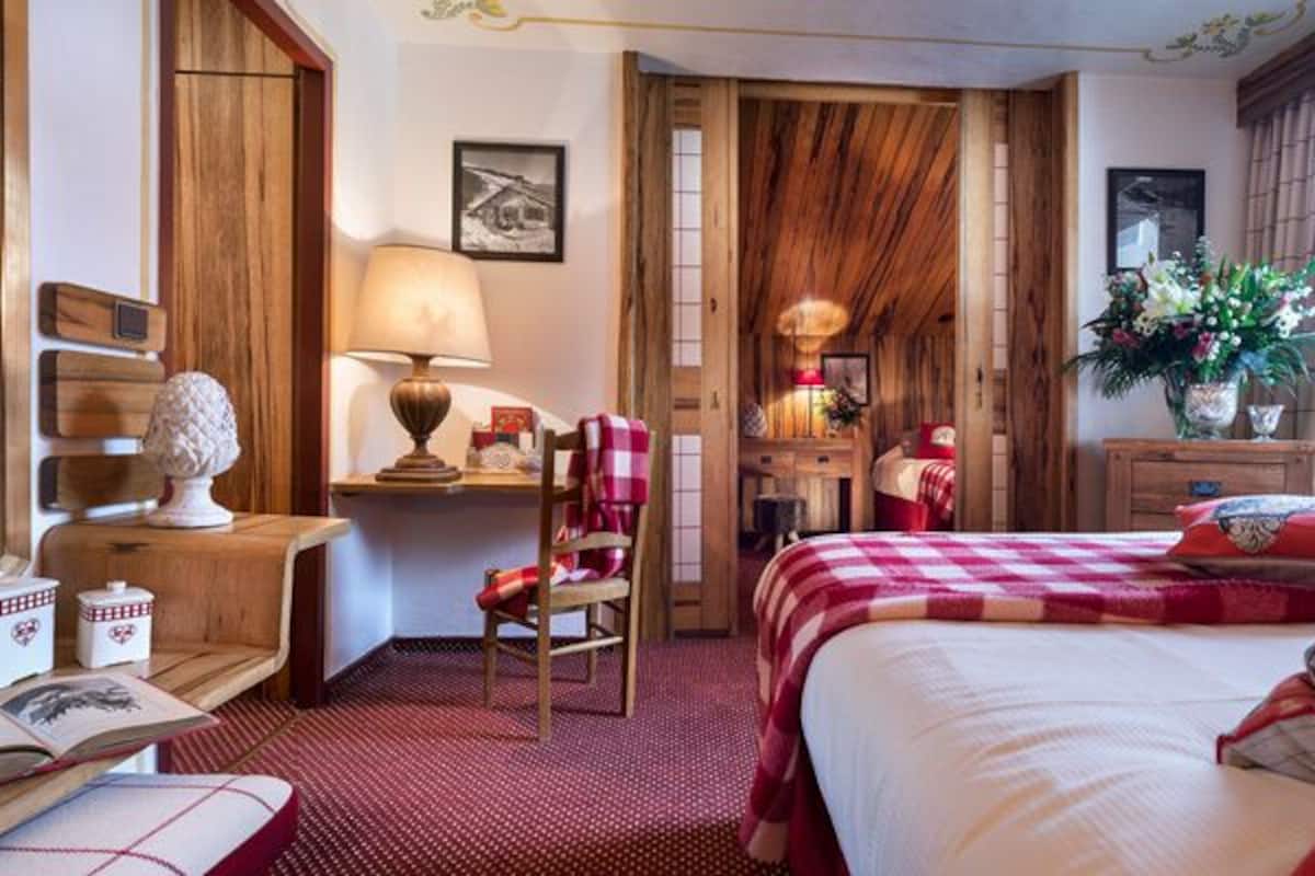 Une chambre confortable avec un grand lit, une commode en bois, une chaise et un bureau avec une lampe.
