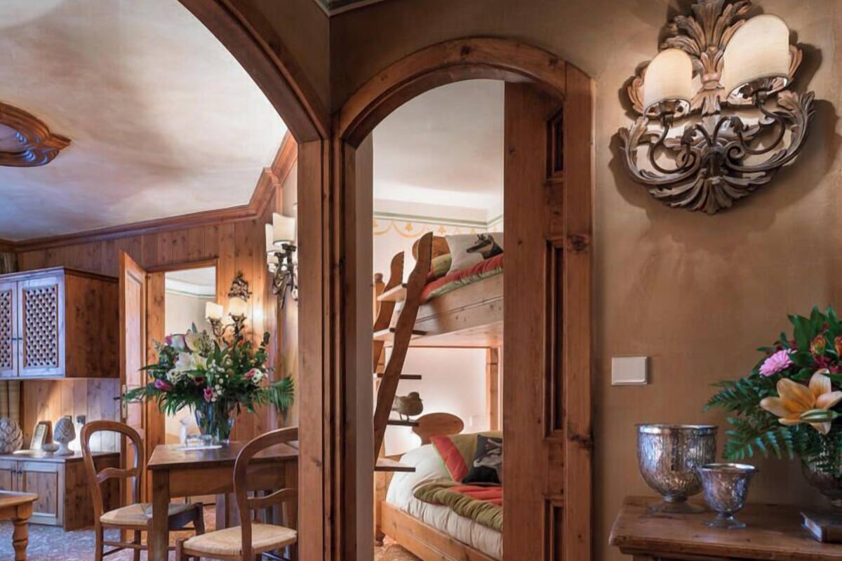 Un intérieur rustique avec des meubles en bois, un coin repas, un lit avec une échelle et un élément décoratif mural.