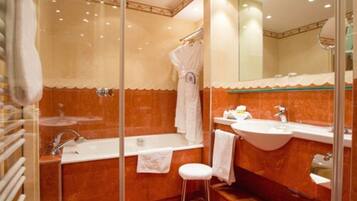 A bathroom with a glass shower enclosure, a bathtub, a sink, and a mirror.