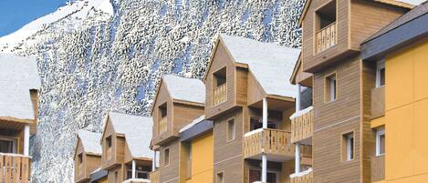 Fila de edificios de madera de varios pisos con balcones, con una imponente montaña nevada al fondo.