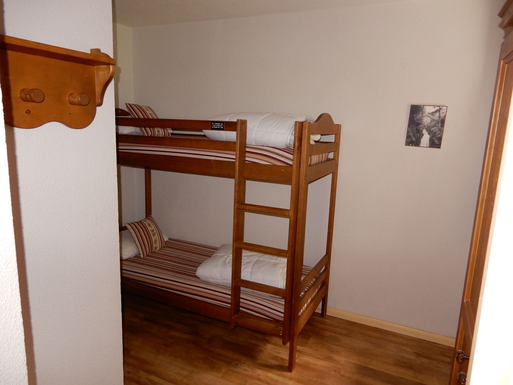 A bunk bed room with a wooden headboard and a small framed picture on the wall.