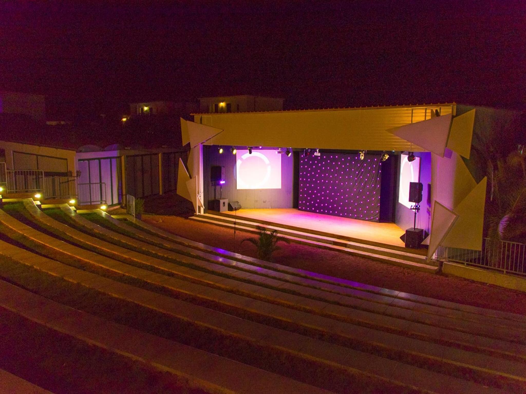 Eine Bühne mit violettem Hintergrund und einem Redner auf einer erhöhten Plattform.