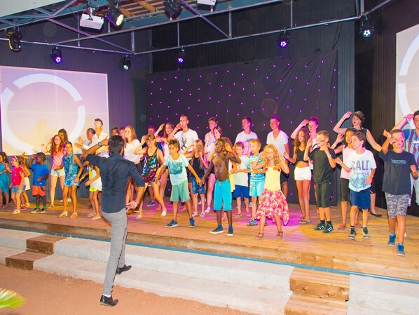 A stage with a group of people performing, possibly a dance or theater act.
