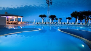Une piscine avec des chaises longues et un moulin à vent.