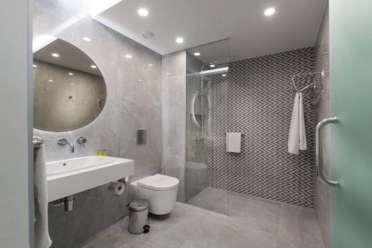 A modern bathroom with a glass shower enclosure, a sink, and a toilet.