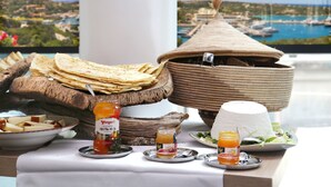 Een ontbijtbuffet met diverse gerechten en toevoegingen op een tafel met een mooi uitzicht op de achtergrond.