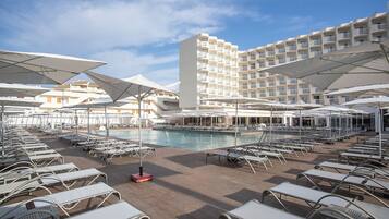 Una piscina al aire libre, sombrillas, sillones reclinables de piscina