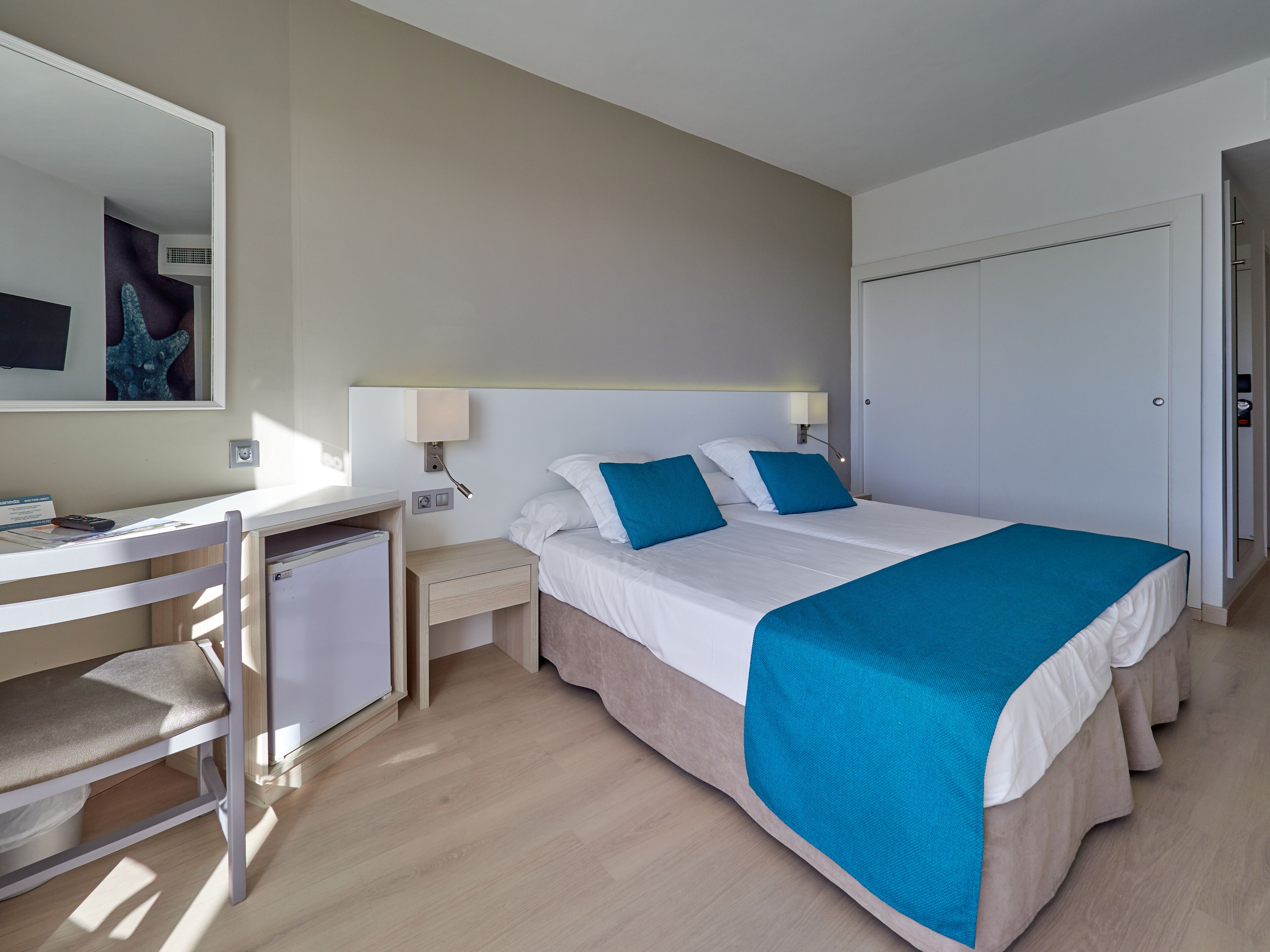 Ein Hotelzimmer mit Bett, Nachttischen, Schreibtisch und Stuhl.