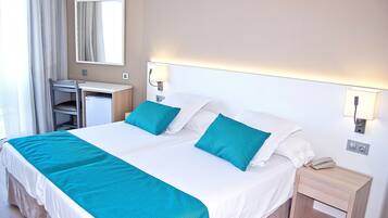 Una habitación de hotel con cama, escritorio, silla, mesita de noche y espejo.