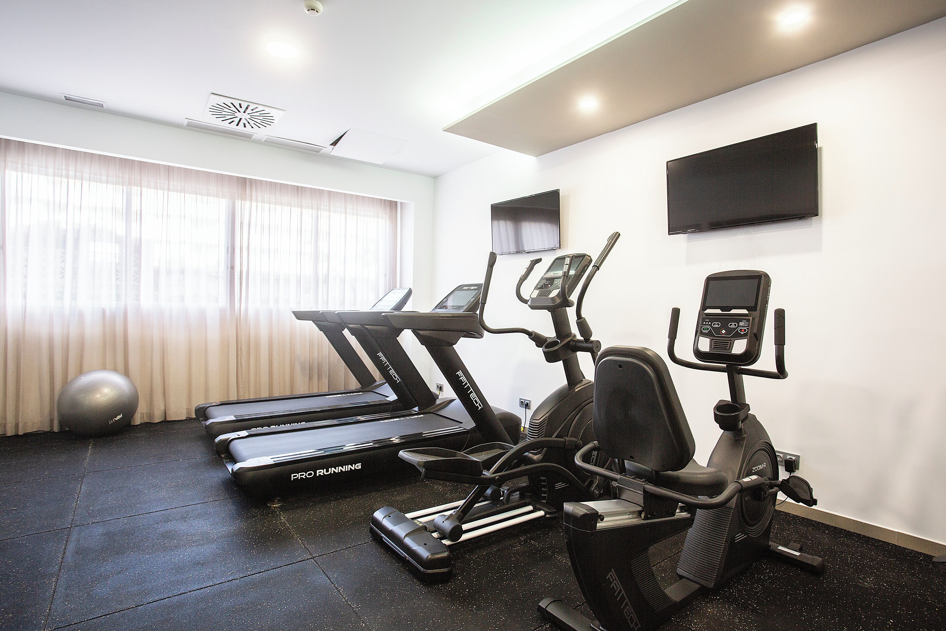 Un gimnasio con cintas de correr, elípticas y bicicletas estáticas.