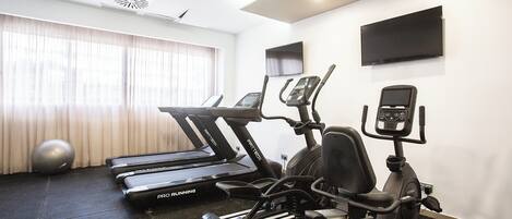 Un gimnasio con cintas de correr, elípticas y bicicletas estáticas.