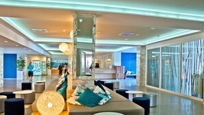 A spacious lobby with seating areas, a reception desk, and large windows. - BQ Delfín Azul Hotel (Alcúdia)