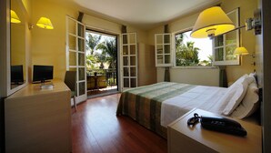 A hotel room with a bed, bedside table, lamp, TV, and a view of the outdoors. - Hotel Borgo Verde (Catania)