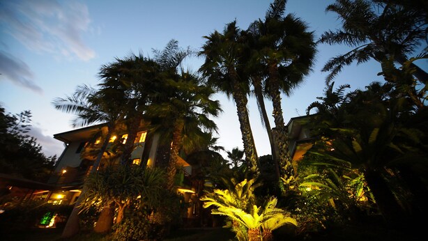 A building with multiple floors, surrounded by palm trees and other tropical vegetation. - Hotel Borgo Verde (Catania)