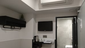 A bathroom with a toilet, sink, and a black shelf with a small plant.