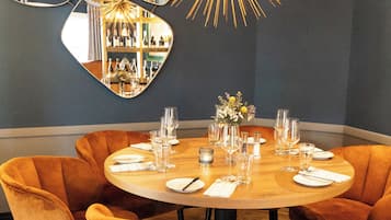 Un comedor con una mesa redonda dispuesta para seis personas, rodeada de seis sillas naranjas.
