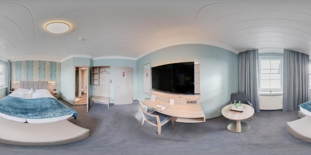 Una habitación de hotel moderna con una cama curvada, un escritorio, un televisor de pantalla plana y una zona de estar.