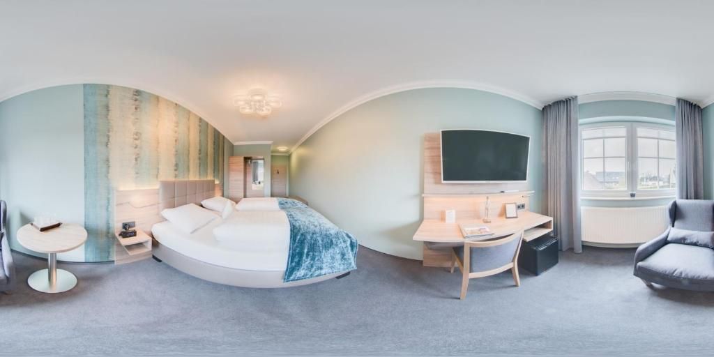 Une chambre d’hôtel moderne avec un lit aux lignes courbes, un bureau, une chaise et une grande fenêtre.