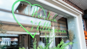 A window with a heart-shaped sign that reads "Herzlich Willkommen" and a checkmark.