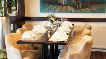 A dining table set for six with a vase of flowers, wine glasses, and a painting on the wall.