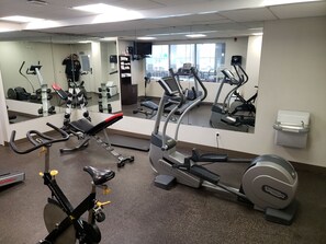 Un gimnasio con varios equipos de ejercicio, incluyendo una máquina de remo, elíptica y bicicleta estática.