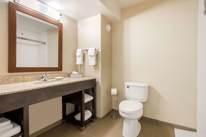 Une salle de bain comprenant un lavabo, un miroir, un porte-serviettes, des toilettes et une petite étagère avec des serviettes.