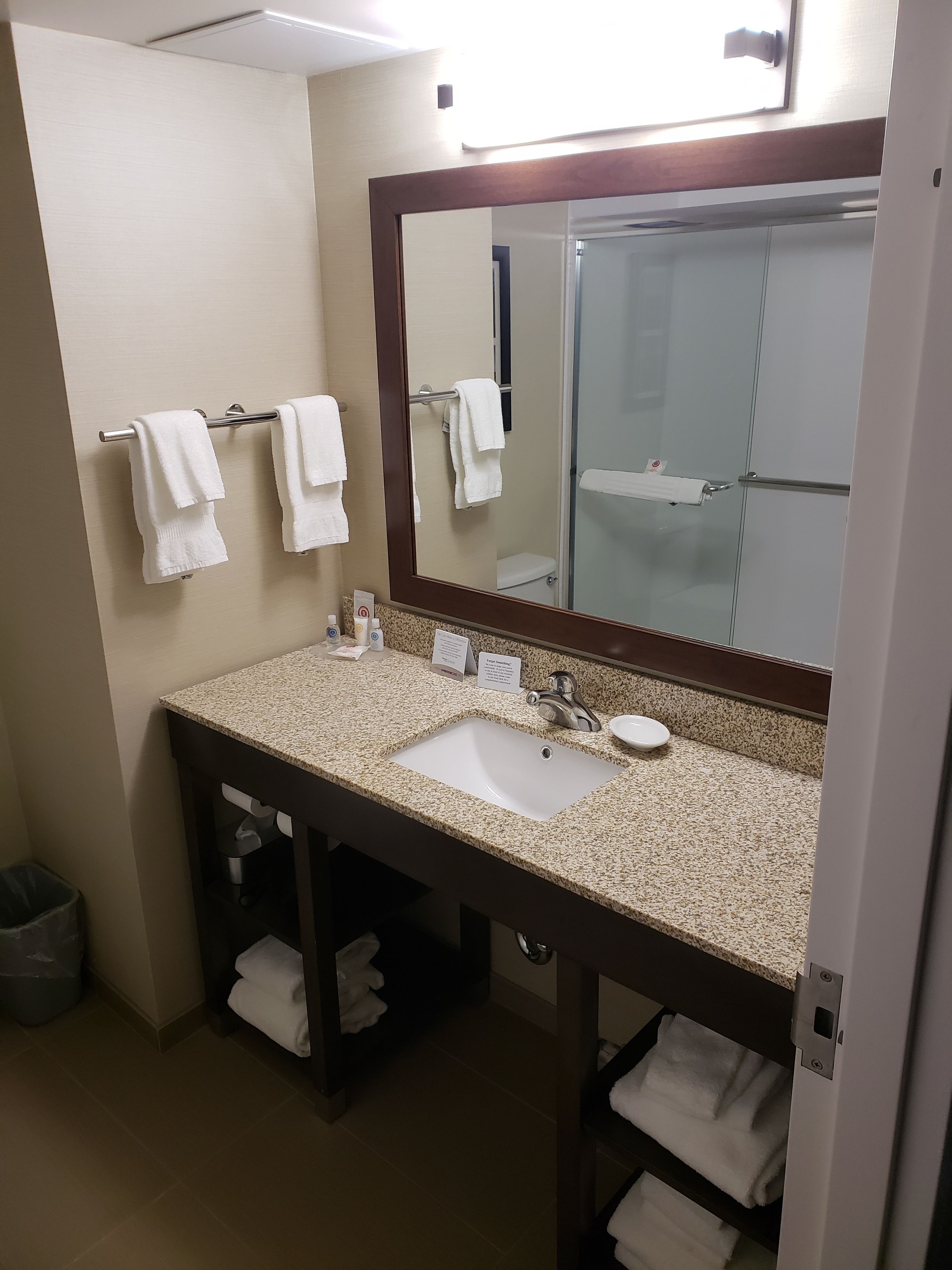 A bathroom with a sink, mirror, towel rack, and a trash bin.