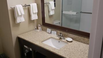 A bathroom with a sink, mirror, towel rack, and a trash bin.